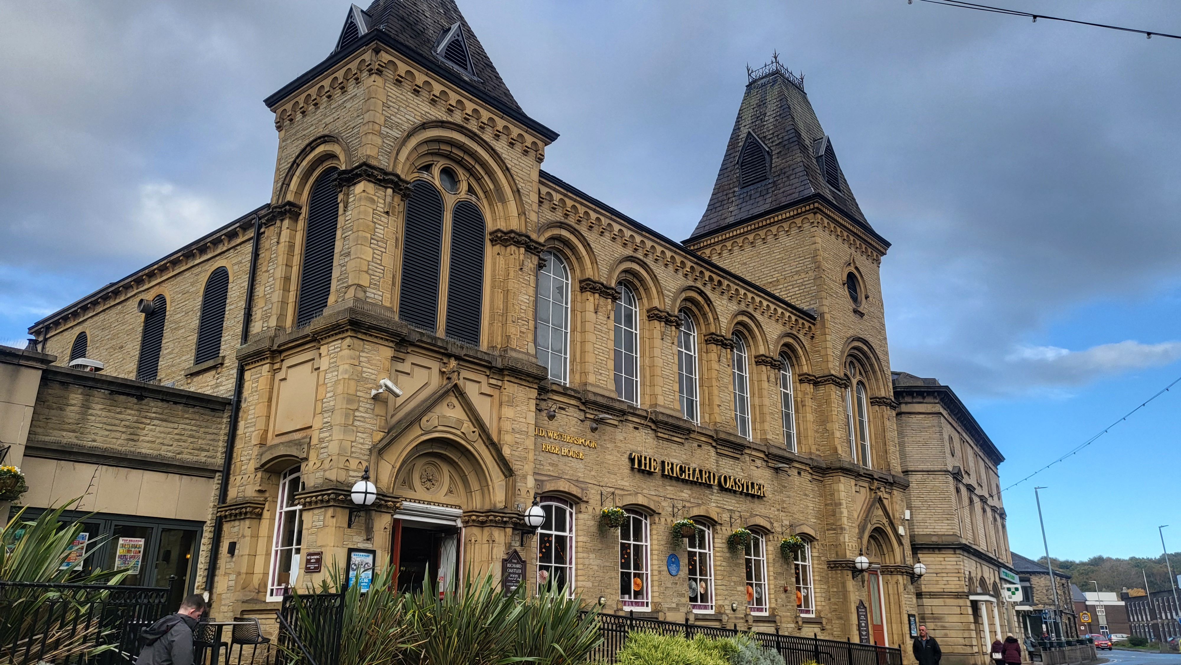 Exterior of Brighouse Wetherspoons, stone building in sunshine with blue sky above