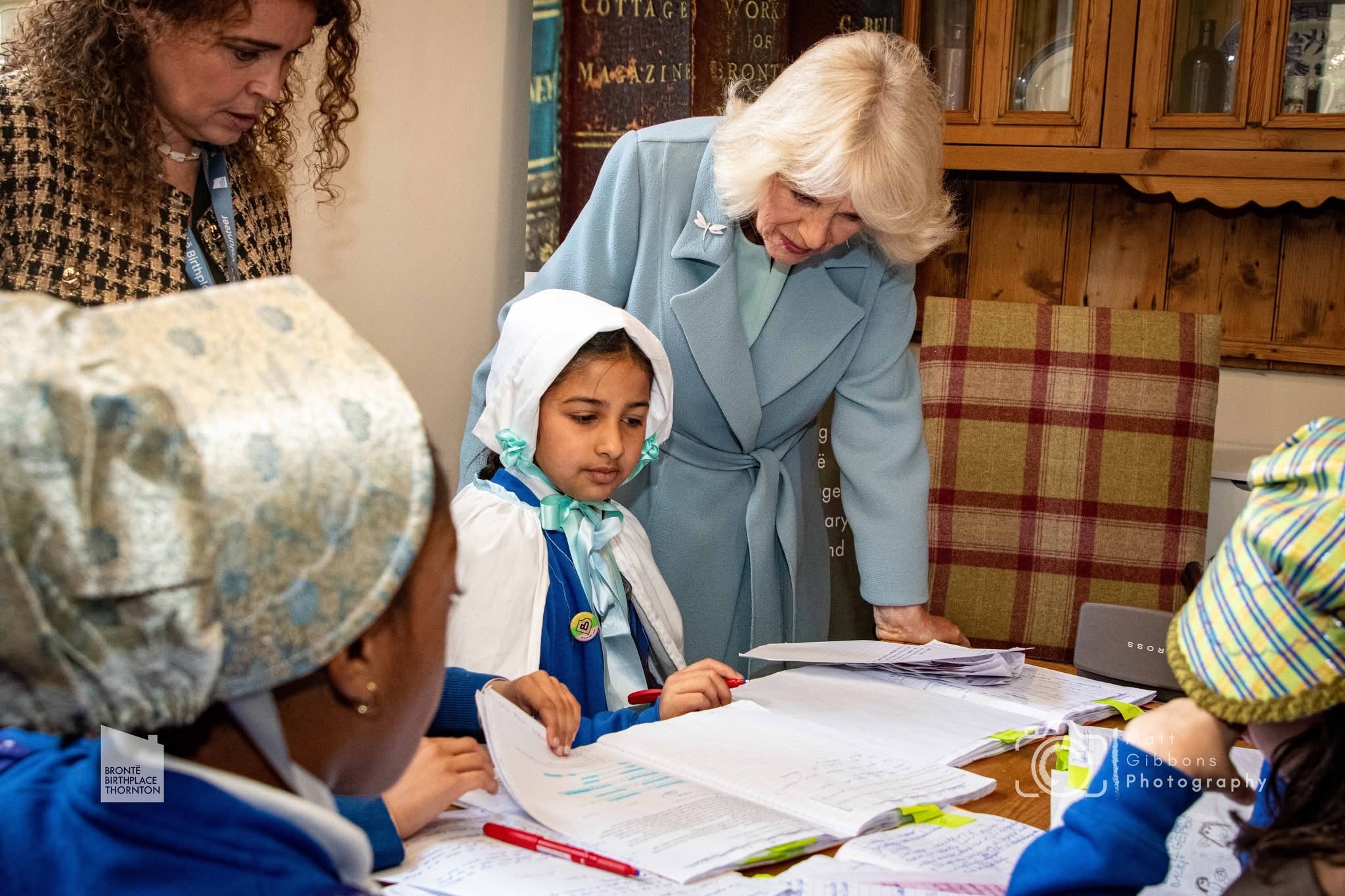Queen Camilla reading with children at table
