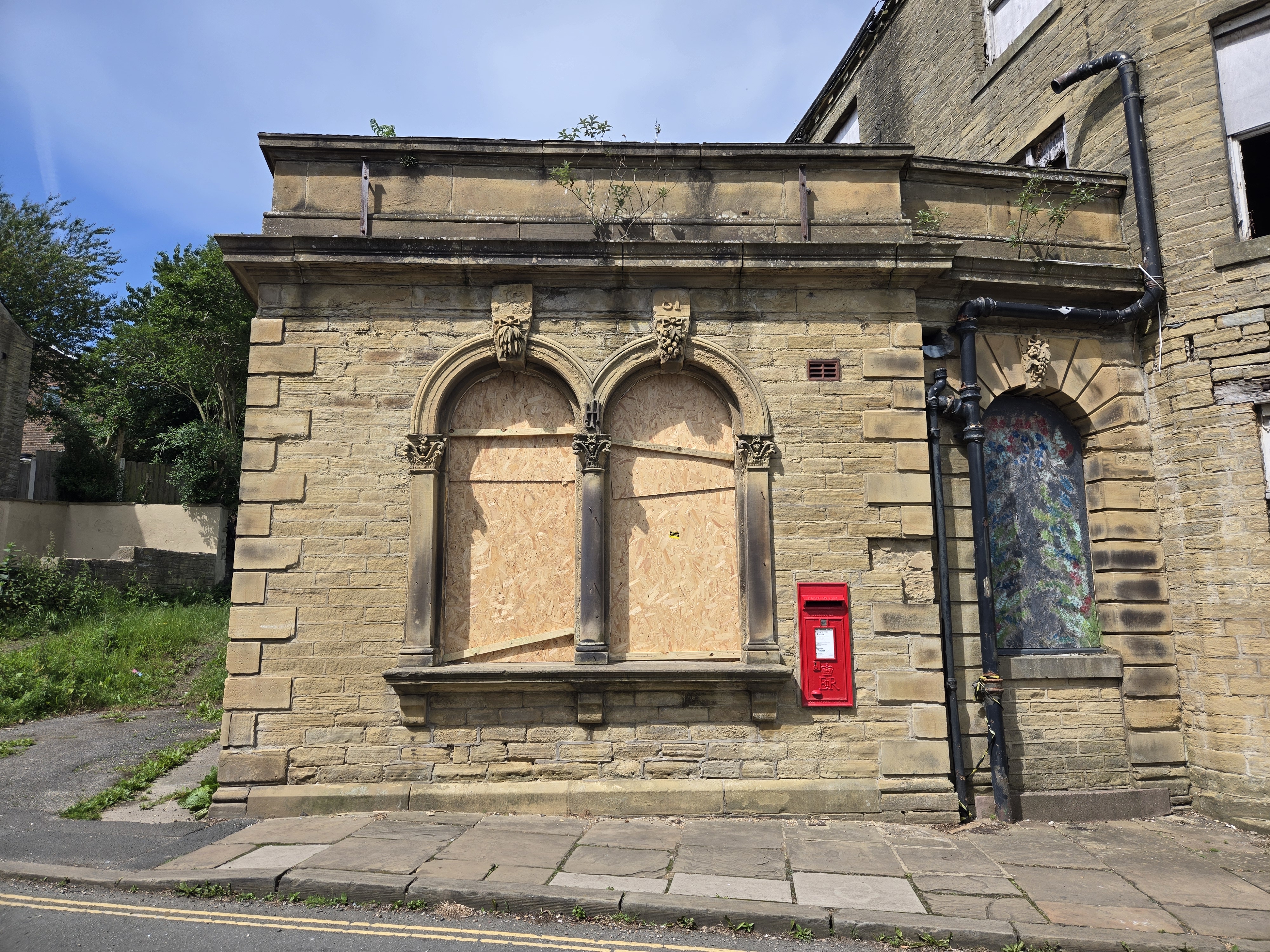 Red postbox on derelict building